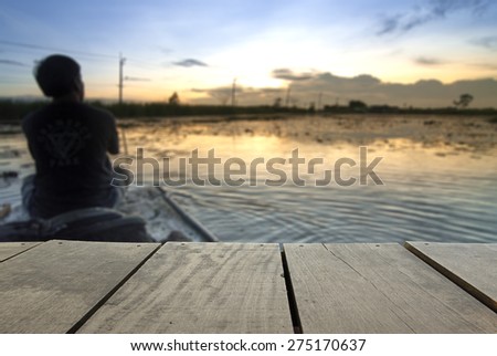 Defocus and blur image of terrace wood and Lonely man sitting on boat at beautiful lake near home for background usage