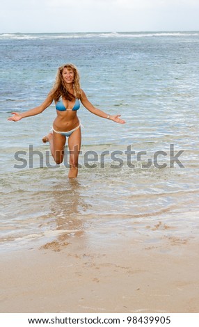 Happy woman in bikini run out from caribbean sea at sunset. Dominican Republic