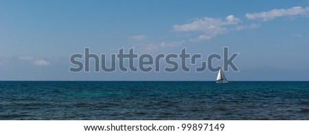 White sailboat sail colorful Mediterranean sea on the horizon