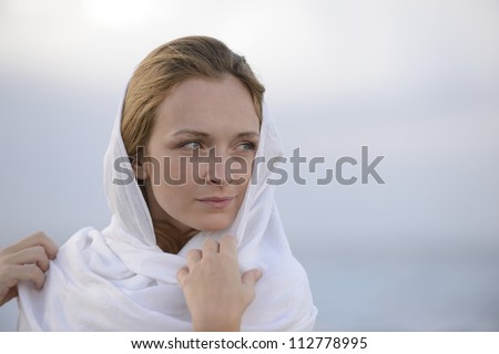 pensive woman with head scarf on the beach