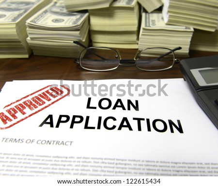 Approved loan application and dollar bills on desk