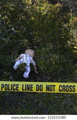 Crime scene in the forest: Yellow police line do not cross tape and doll