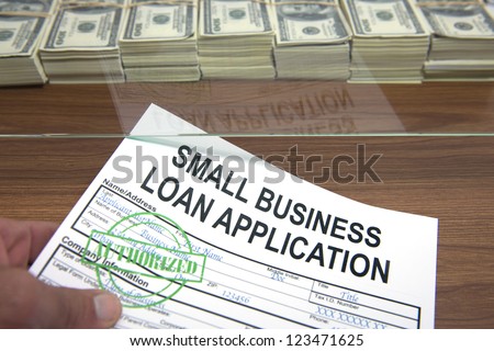Approved small business loan application and dollar bills