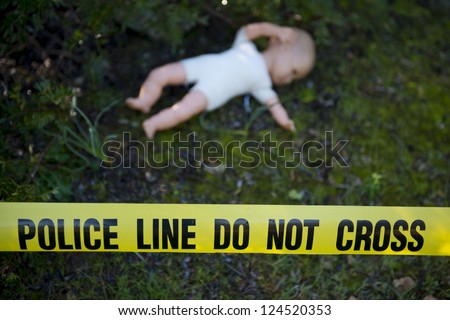 Crime scene in the forest: Yellow police line do not cross tape and doll