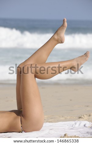 Woman showing her shaved or waxed legs on the beach