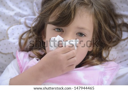 Sick Little Girl Sneezing In Bed