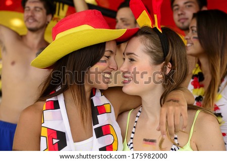 Cheerful couple of German lesbian soccer fans almost kissing celebrating victory.