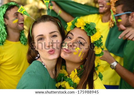Group of Brazilian girls soccer fans commemorating victory posing kissing.