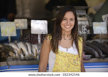 Happy beautiful woman buying fish at a fish shop street market.