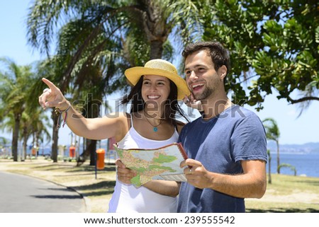 Happy tourist couple with map pointing at destination