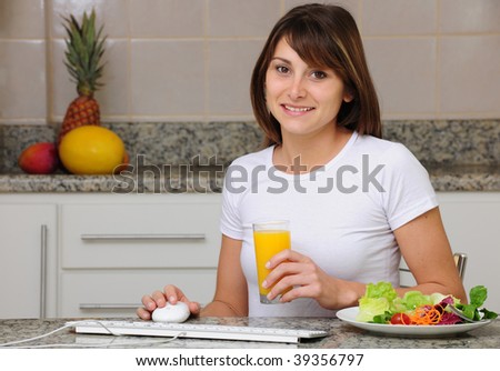 woman eating a salad and working on computer at home
