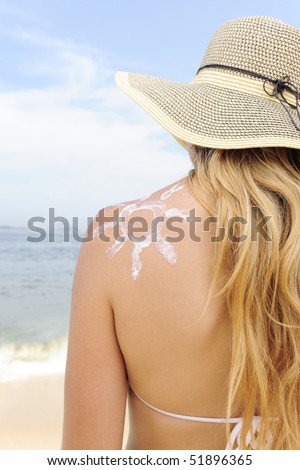 woman with suntan lotion at the beach in form of the sun