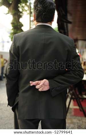 liar: businessman with fingers crossed behind his back