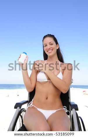 summer vacation: woman in wheelchair applying sunscreen on the  beach