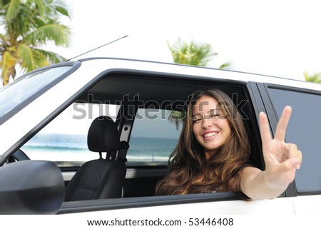 car rental: happy woman in her car near the beach showing victory sign