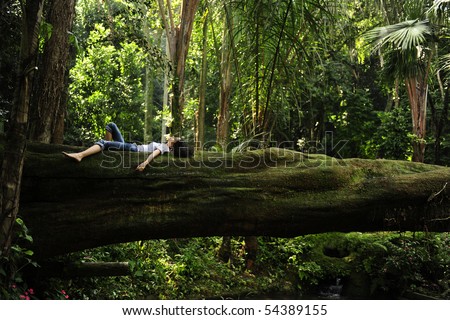 harmony in nature: woman relaxing on a fallen tree trunk in a tropical forest