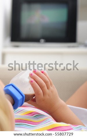 Child drinking chocolate milk in a bottle, lying alone on the couch and watching TV in DVD file