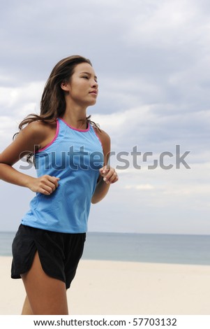 happy female runner running outdoors at the beach