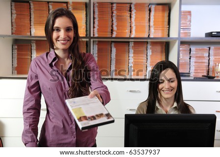 Happy women handing over dvd at the video rental store