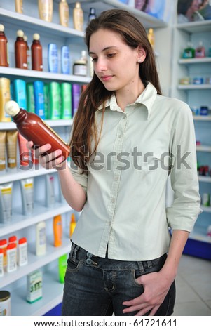 happy woman at pharmacy buying shampoo and reading label