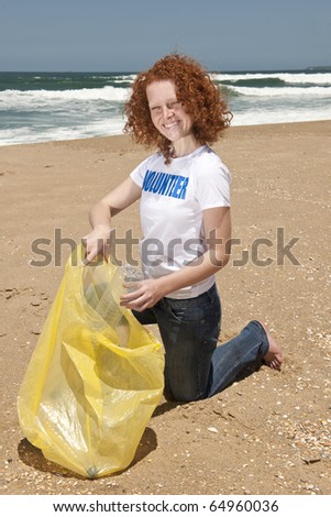 Young female volunteer collecting garbage on beach
