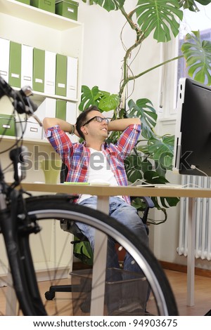 Green business: Man at office thinking about sustainability, responsibility and ecofriendly future. His bike in the foreground