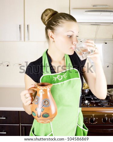 Young woman drinking water in the kitchen