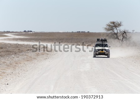 ETOSHA, NAMIBIA - OCTOBER 27 2013: Safari Truckdrives on dusty road in a year of drought at Etosha National Park, Namibia, Africa