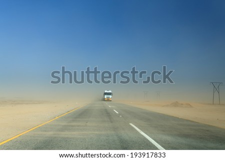 SWAKOMPUND, NAMIBIA - OCTOBER 31 2013: In a year of drought goods vehicle drives through a sand storm through the Namib desert at Swakompmund, Namibia, Africa