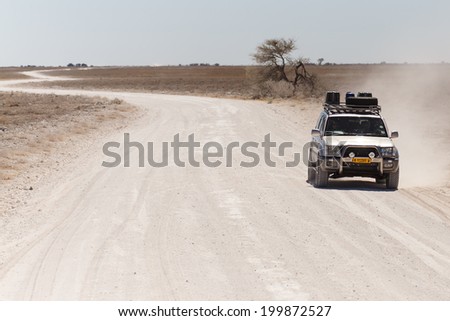 ETOSHA, NAMIBIA - OCTOBER 27 2013: Safari Truckdrives on dusty road in a year of drought at Etosha National Park, Namibia, Africa