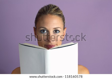 young woman reading a book with white covers quietly in a purple background