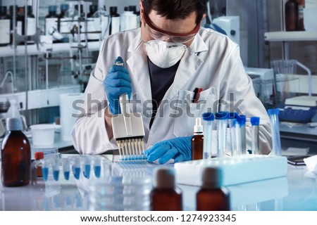 lab technician pipetting plate in the genetic laboratory / scientist working with multi well plate for cell culture in the lab