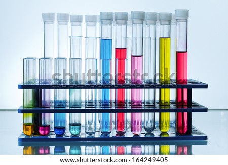 rack with chemical test tubes with colored fluid in laboratory blue background