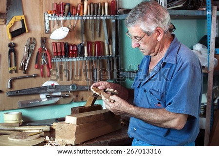 horizontal portrait of carpenter examining handmade pieces of wood workshop / work cabinetmaker looking handcrafted wooden pieces in garage at home