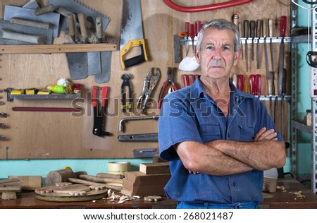 Portrait of a worker in work clothes in front of workbench tools / Portrait of man at work in workshop in garage at home