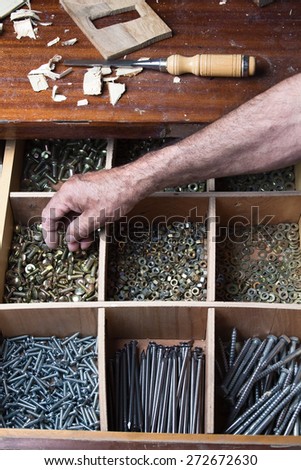 Desk drawer of a cabinetmaker working with several compartments with nuts, screws, nails, bolts / the drawer screws