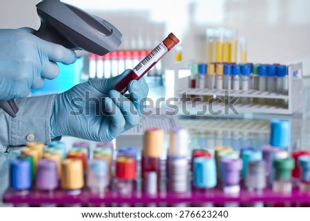 technician hands scanning barcodes on biological sample tube in the lab of blood bank / doctor scanning a tube with barcode label for tracking of blood sample