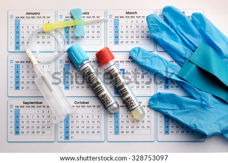blood tubes, needle and gloves on the bottom of an appointment calendar in lab table / utensils to perform a blood test at the hospital