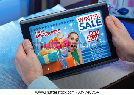 man searching website internet store to purchase online in Winter Sale with your tablet in you home / hands of a man in web tablet at a website with an announcement concept purchase Winter Sale online