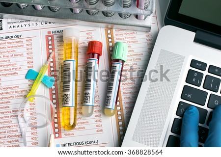 flat lay of workbench with tubes labeled, laptop and report for blood test / top view of a work table of lab with test tubes for analysis and computer