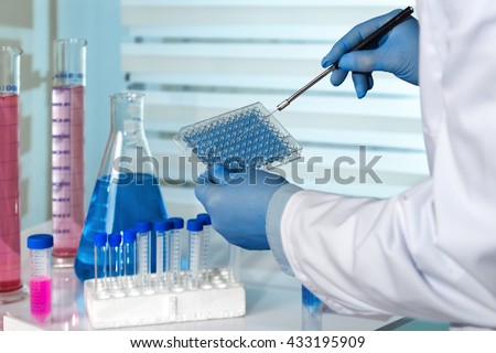 scientist working in a pharmaceutical lab / biomedical engineer working with microplate in laboratory