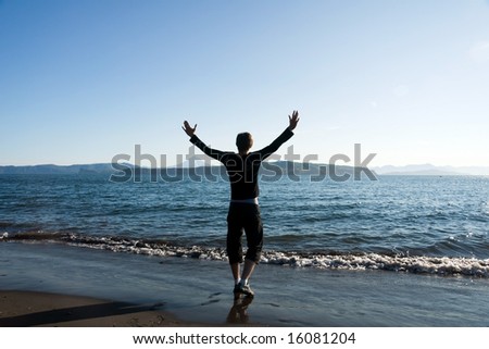 man stands on beach having stretched hands on sunset at night