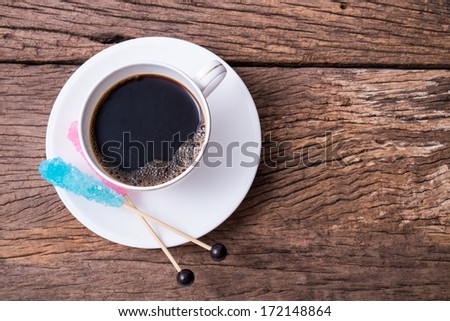 Hot black coffee on the wooden table with colorful sugar party stick