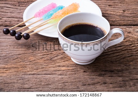 Hot black coffee on the wooden table with colorful sugar party stick