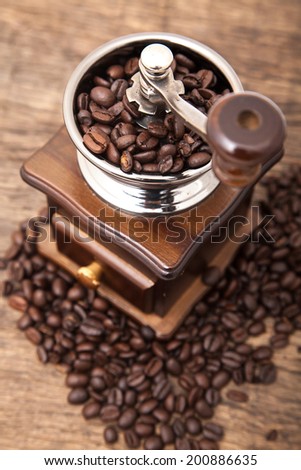 Close up fresh coffee bean in coffee bean grinder next to coffee bean on wooden table top