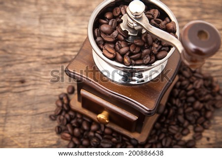 Close up fresh coffee bean in coffee bean grinder next to coffee bean on wooden table top