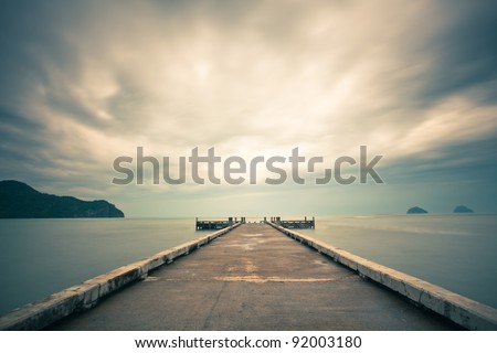 Cloudscape over sea with pier in foreground.
