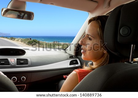 Couple enjoying their new car on a coastal road - Woman looks at man with tenderness