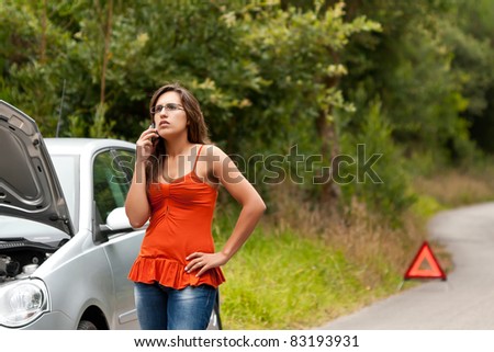 A woman calls for assistance using her mobile phone, after her car broke down on the road side