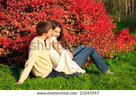 Happy young couple in love meeting in the autumn park with red leaves